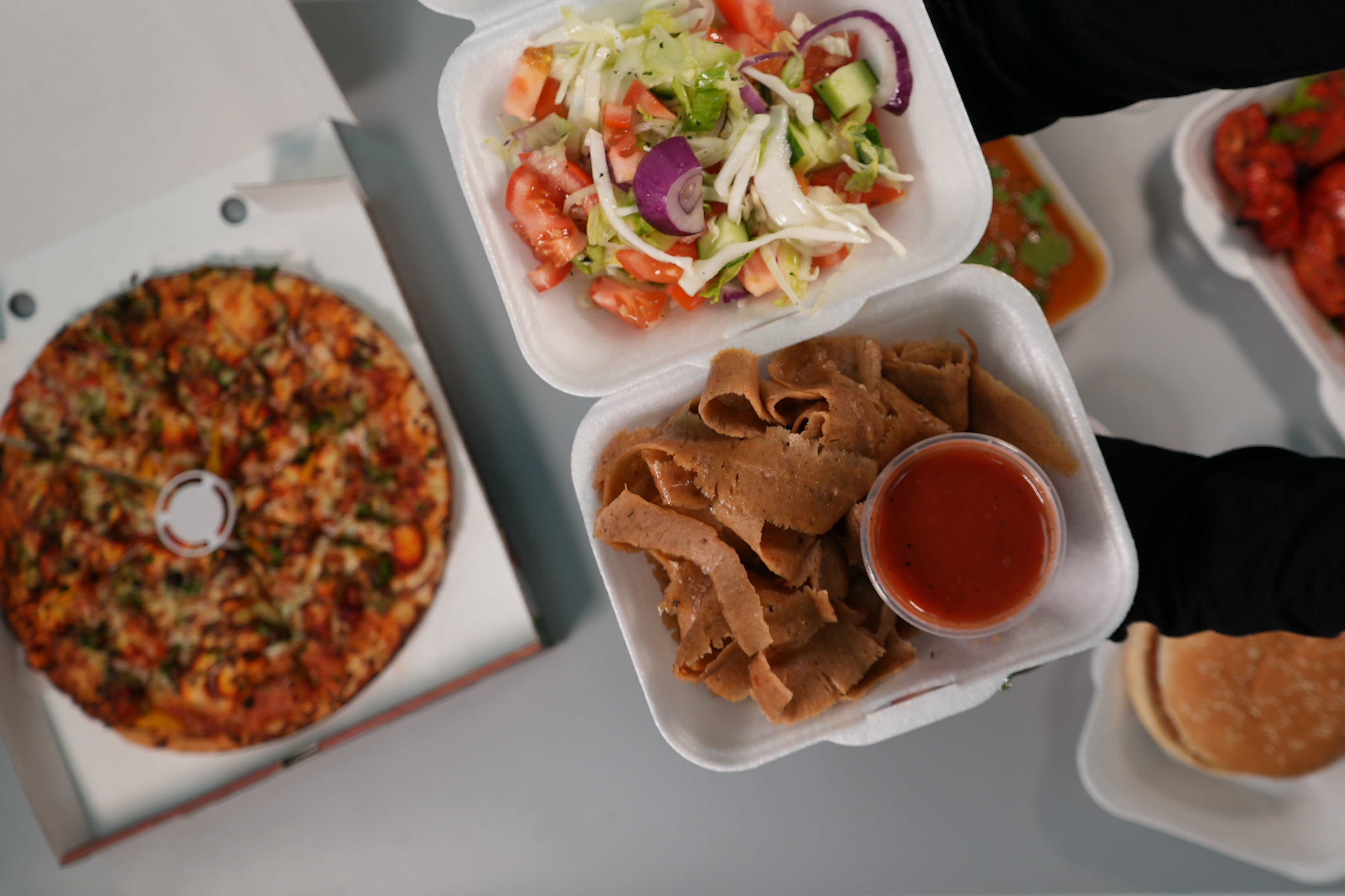 slicing thin layers of meat from a large rotating doner kebab in Paprikas Nicos Johnstone