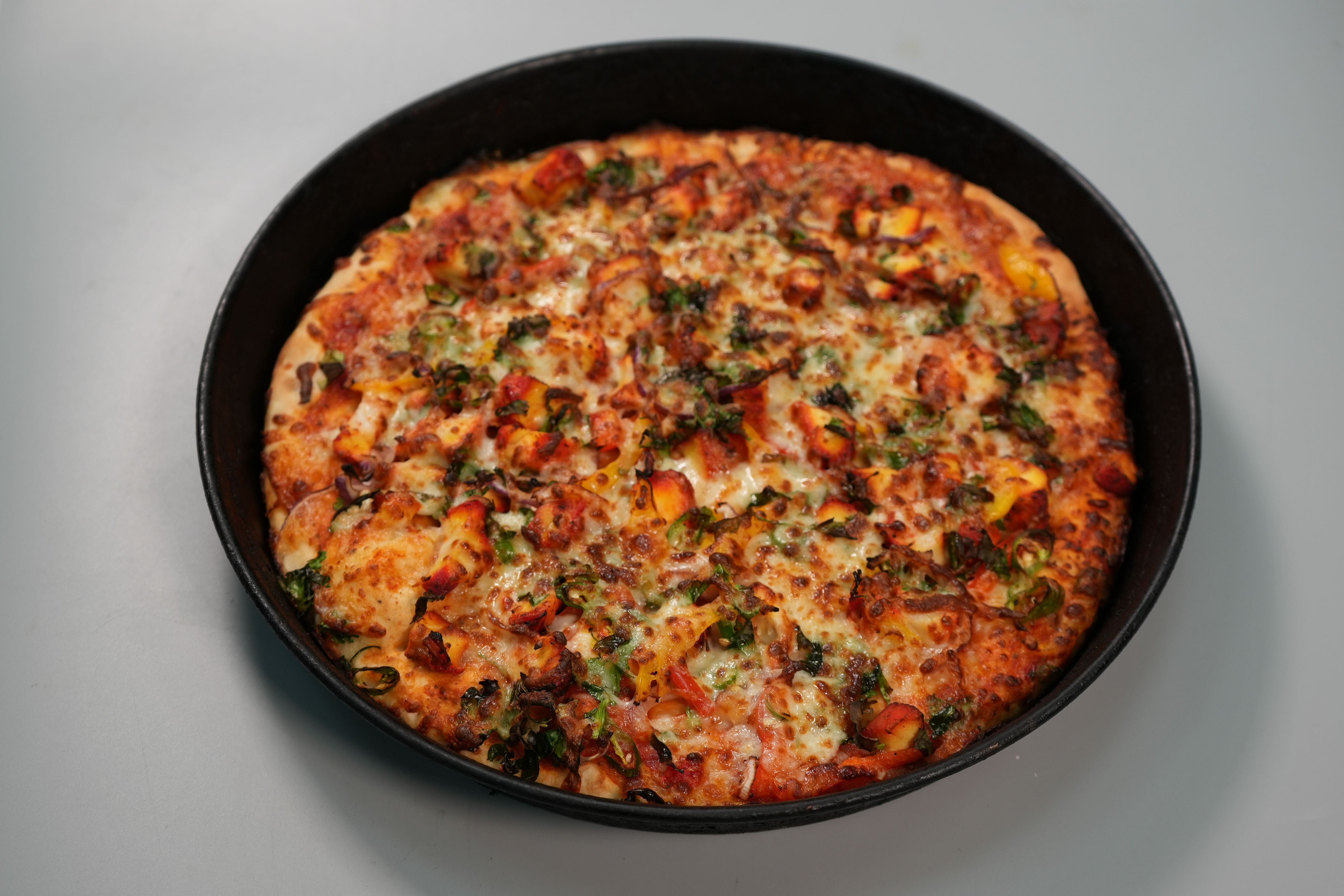 a freshly made pizza loaded with toppings served at Paprikas Nicos Johnstone